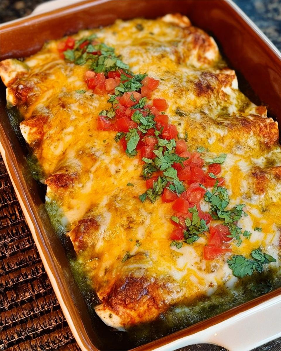 Close-up of cheesy chicken enchiladas topped with diced tomatoes and cilantro, perfect for chicken recipes meal prep.