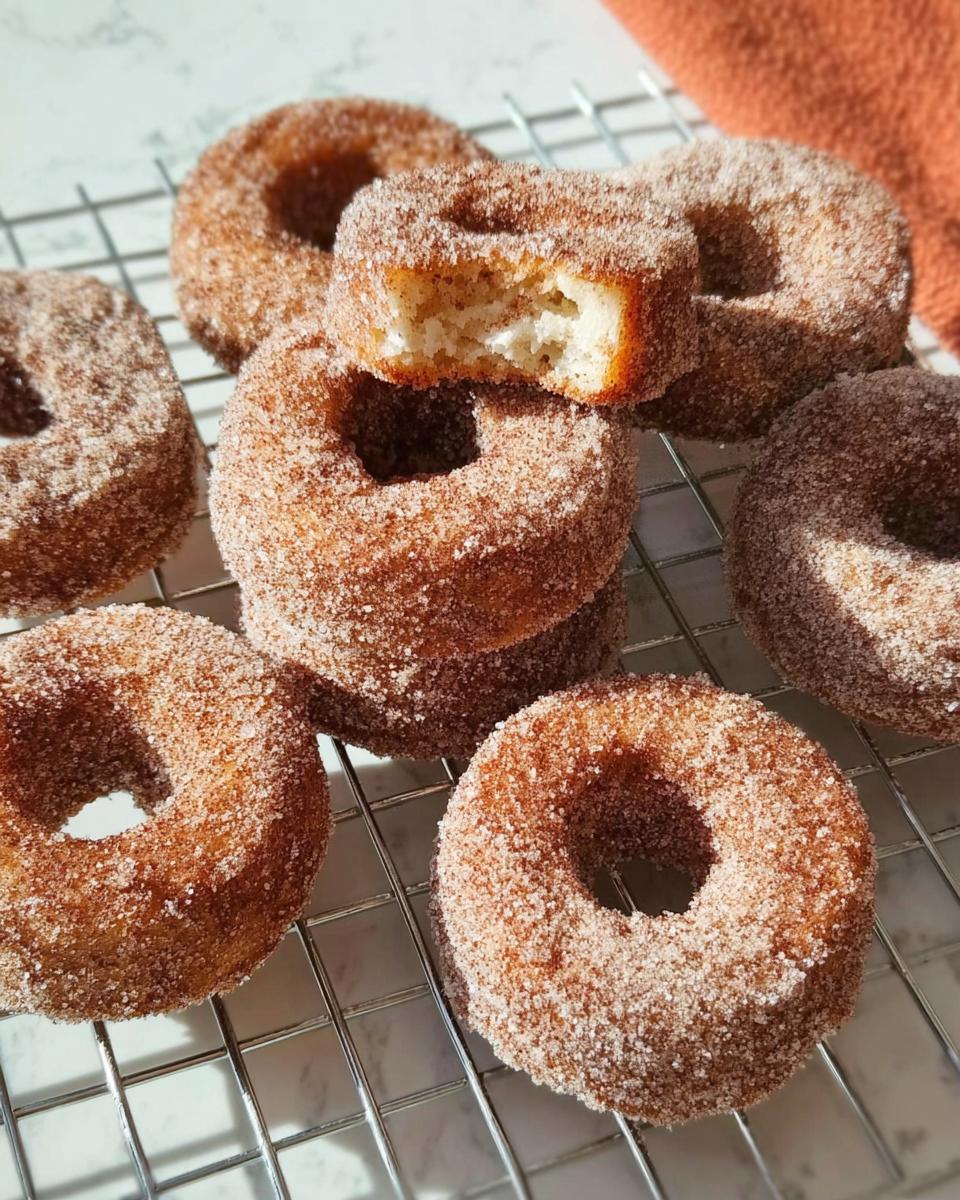 A batch of freshly baked cinnamon sugar donuts, with one donut broken in half to show the fluffy interior. Perfect for breakfast ideas.