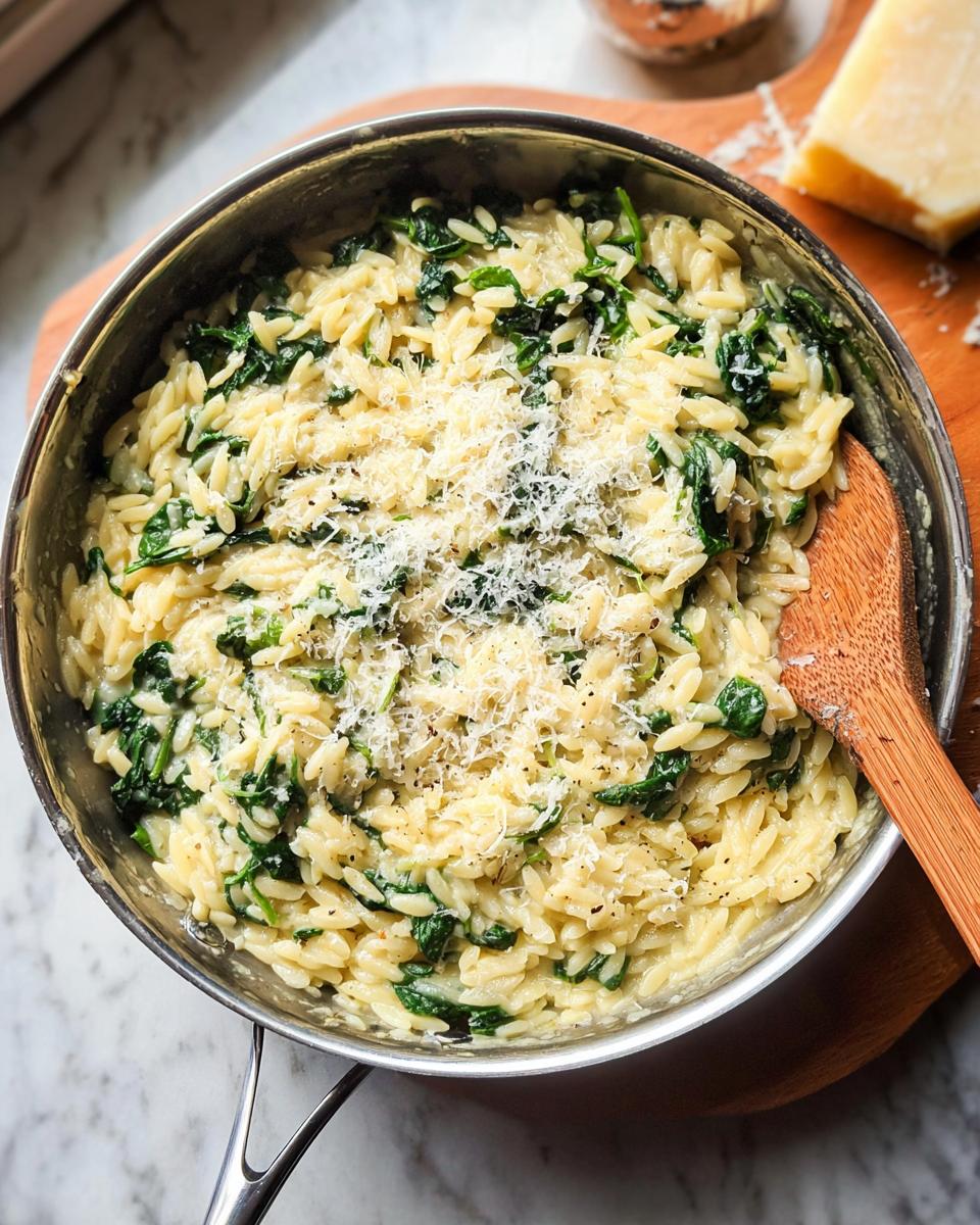 Close-up of creamy orzo pasta with spinach, topped with grated parmesan cheese, a perfect veggie side dish.