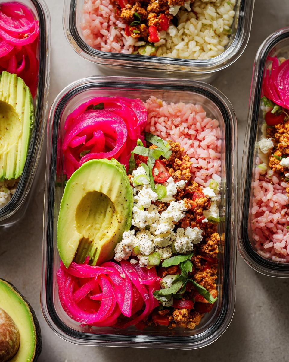 Overhead view of meal prep containers filled with rice bowls featuring pink rice, crumbled tofu, avocado slices, and bright pink pickled onions.
