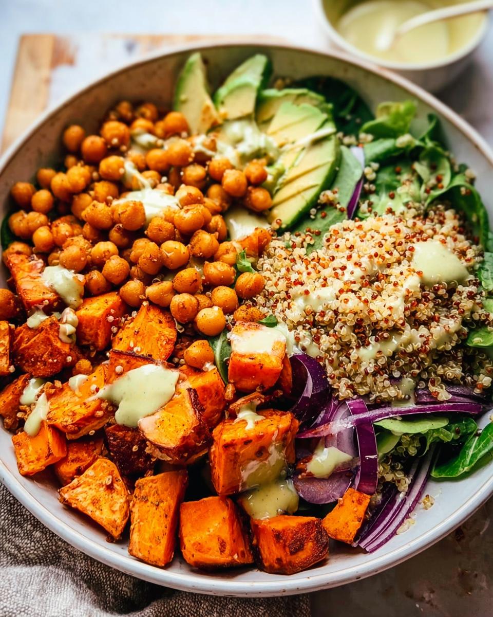 A vibrant and healthy rice bowl recipe featuring roasted sweet potatoes, chickpeas, quinoa, avocado, and red onion, drizzled with a creamy dressing.