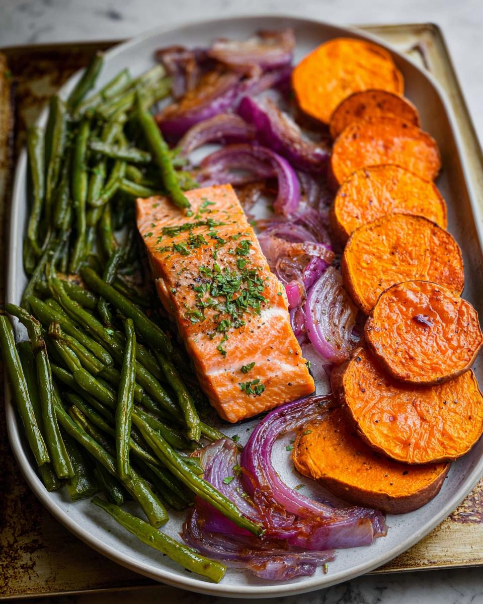 A perfectly cooked salmon fillet served with roasted sweet potatoes, green beans, and red onions, ideal for salmon recipes meal prep.