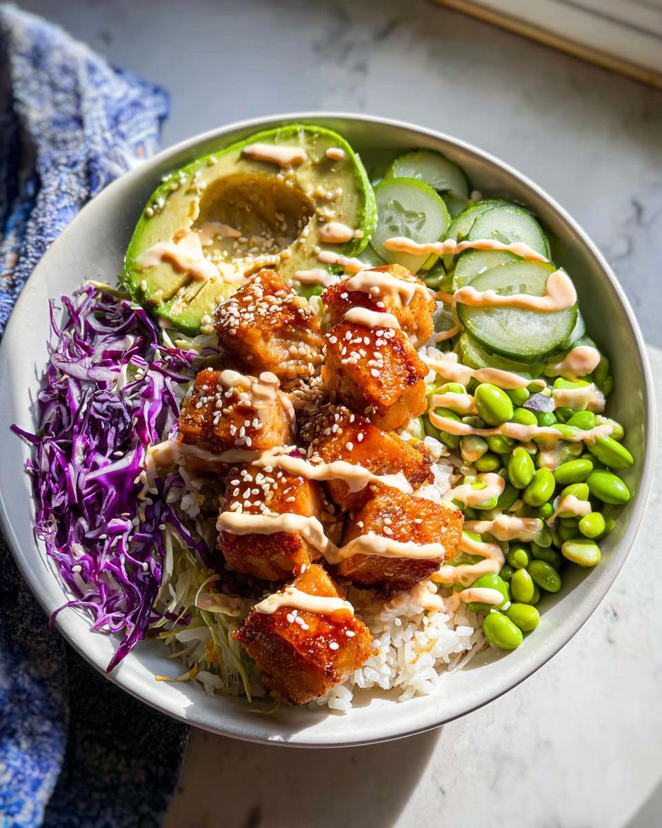 A vibrant Crispy Salmon and Rice Bowl topped with avocado, cucumber, edamame, and shredded cabbage.