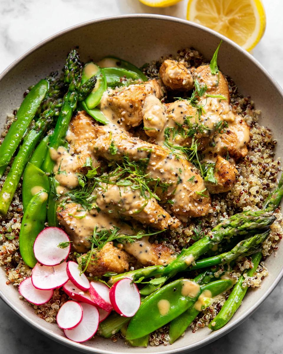 A vibrant bowl of Healthy Lemon Garlic Chicken Meal Prep, featuring quinoa, chicken, asparagus, snap peas, and radishes.
