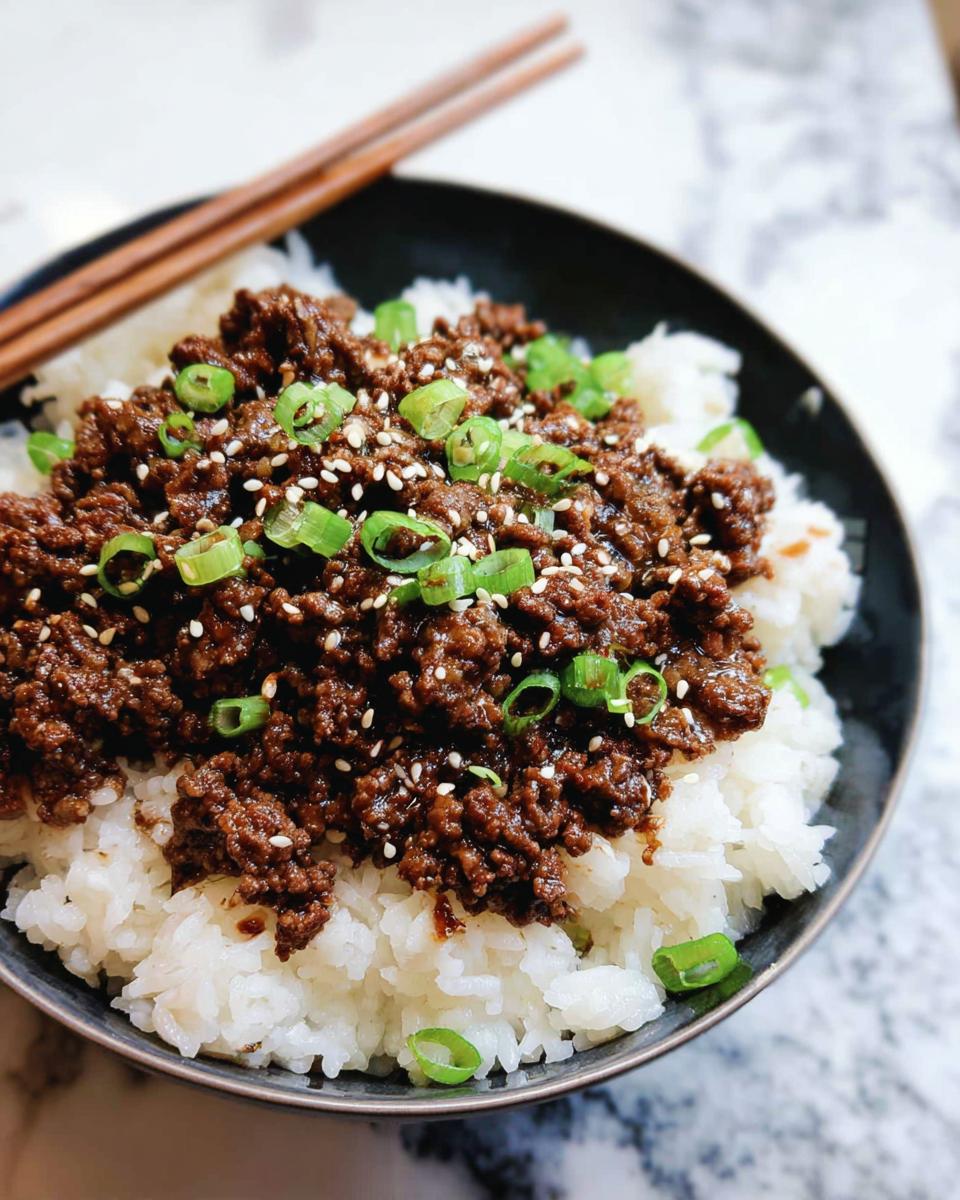 A close-up of a Korean Ground Beef Bowl, featuring seasoned ground beef over white rice, garnished with sesame seeds and chopped green onions.