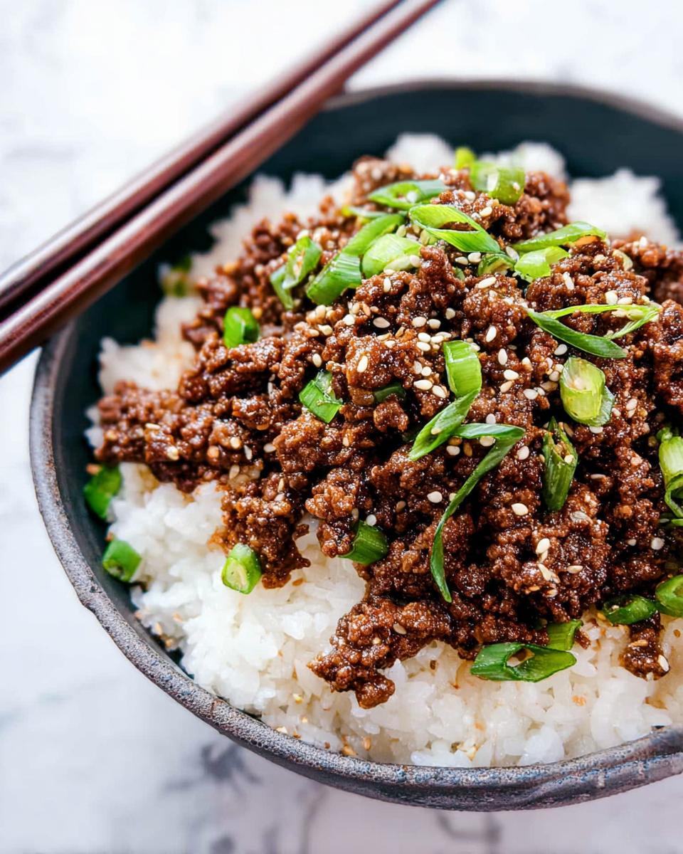 Close-up of a Korean Ground Beef Bowl, featuring savory ground beef over fluffy white rice, garnished with green onions and sesame seeds.