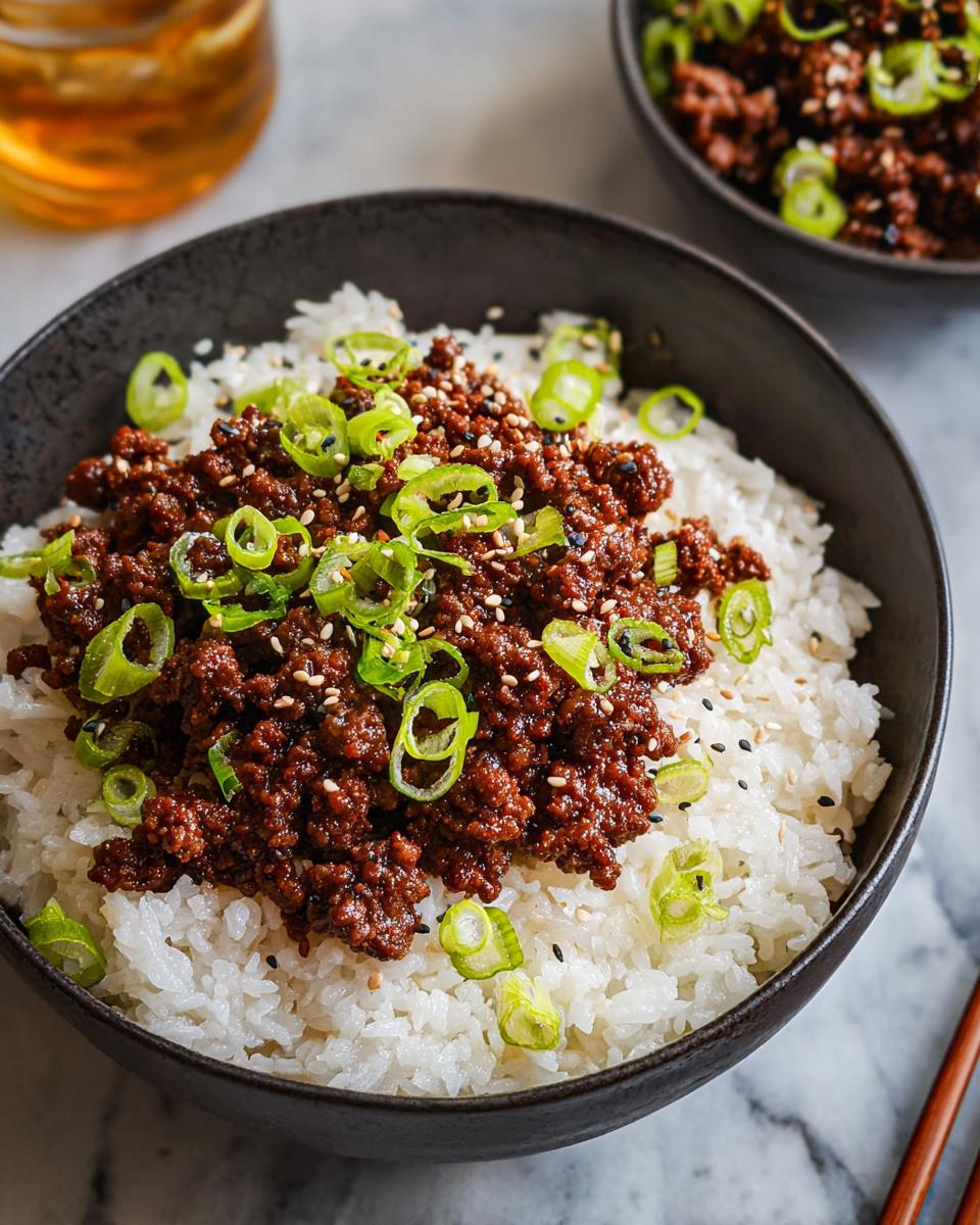 A close-up of a Korean Ground Beef Bowl, featuring savory ground beef over fluffy white rice, topped with fresh green onions and sesame seeds.