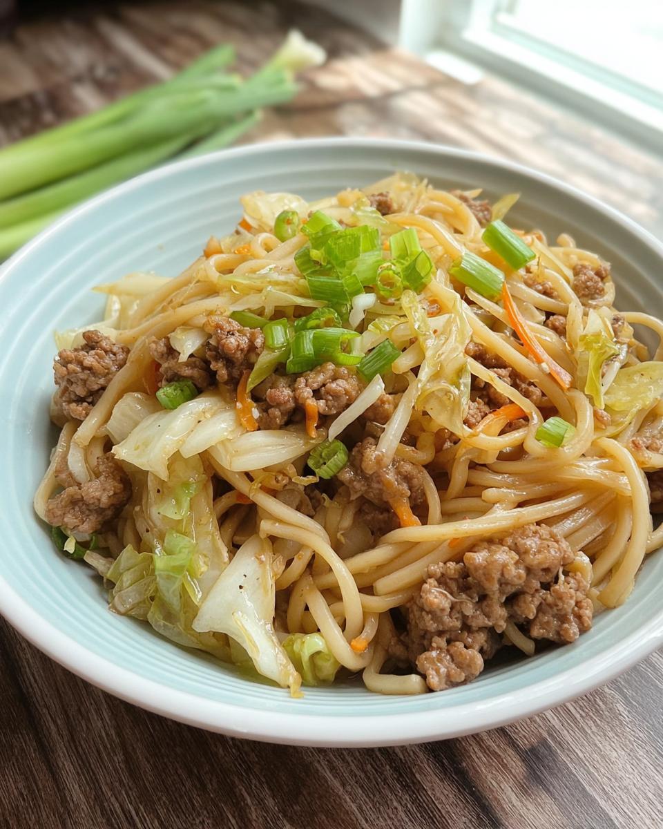 A close-up of a bowl filled with Potsticker Noodle Bowl with Pork & Cabbage Slaw, garnished with green onions.