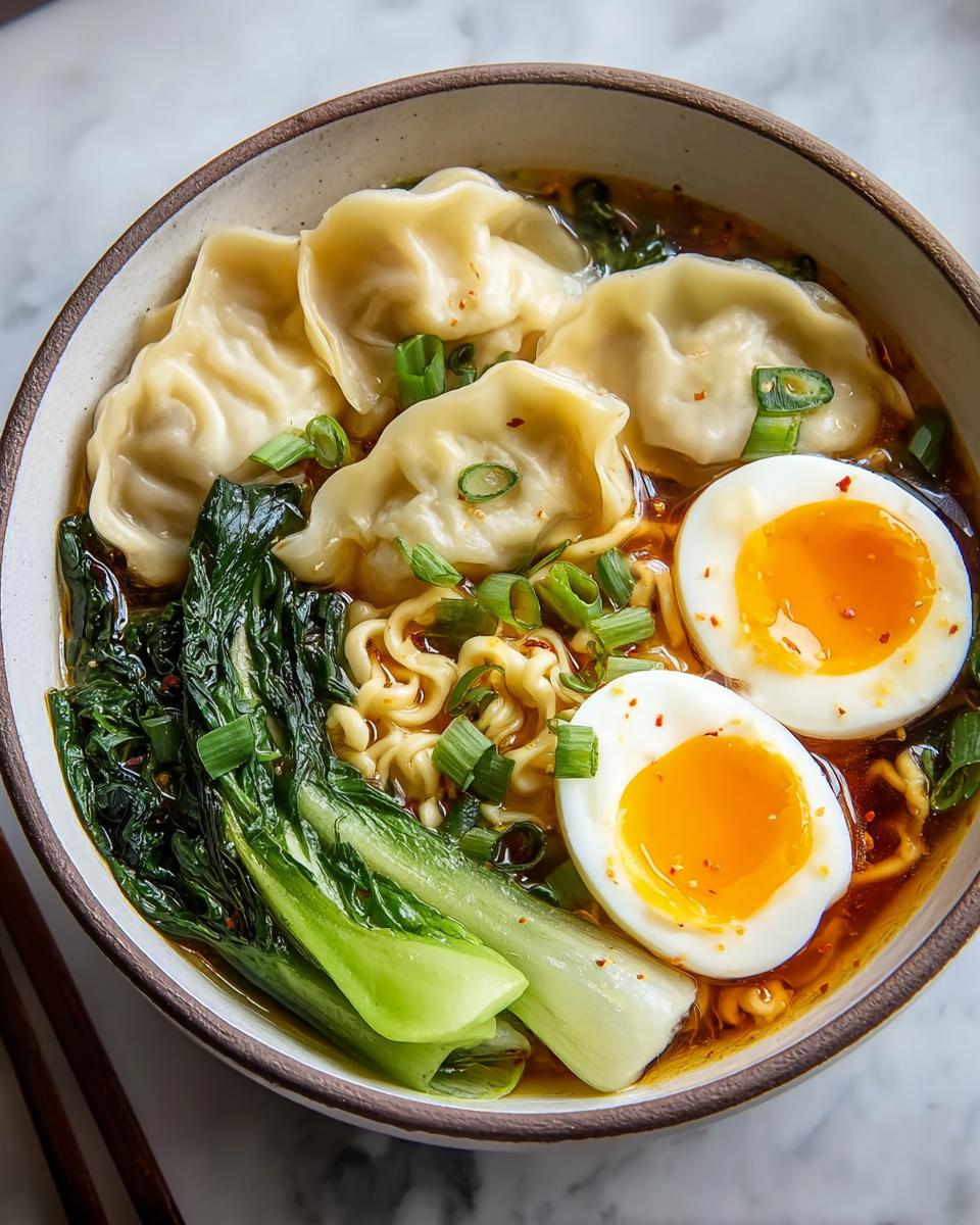 A delicious bowl of Savory Dumpling Ramen with soft-boiled eggs, bok choy, and noodles, garnished with green onions.