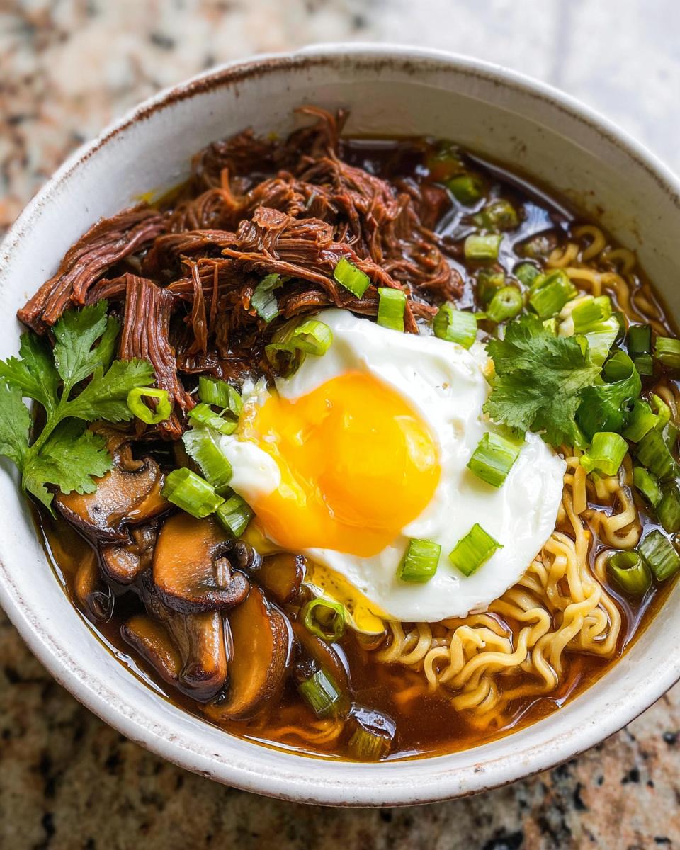 A bowl of Slow Cooker Beef Ramen Noodles topped with a fried egg, mushrooms, and green onions.