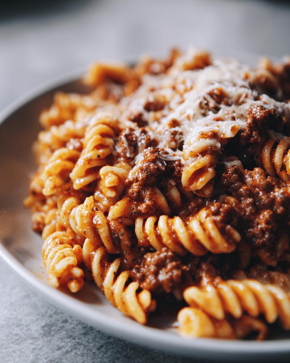 Close-up of Creamy High Protein Beef Pasta with fusilli noodles and a rich meat sauce, topped with shredded cheese.