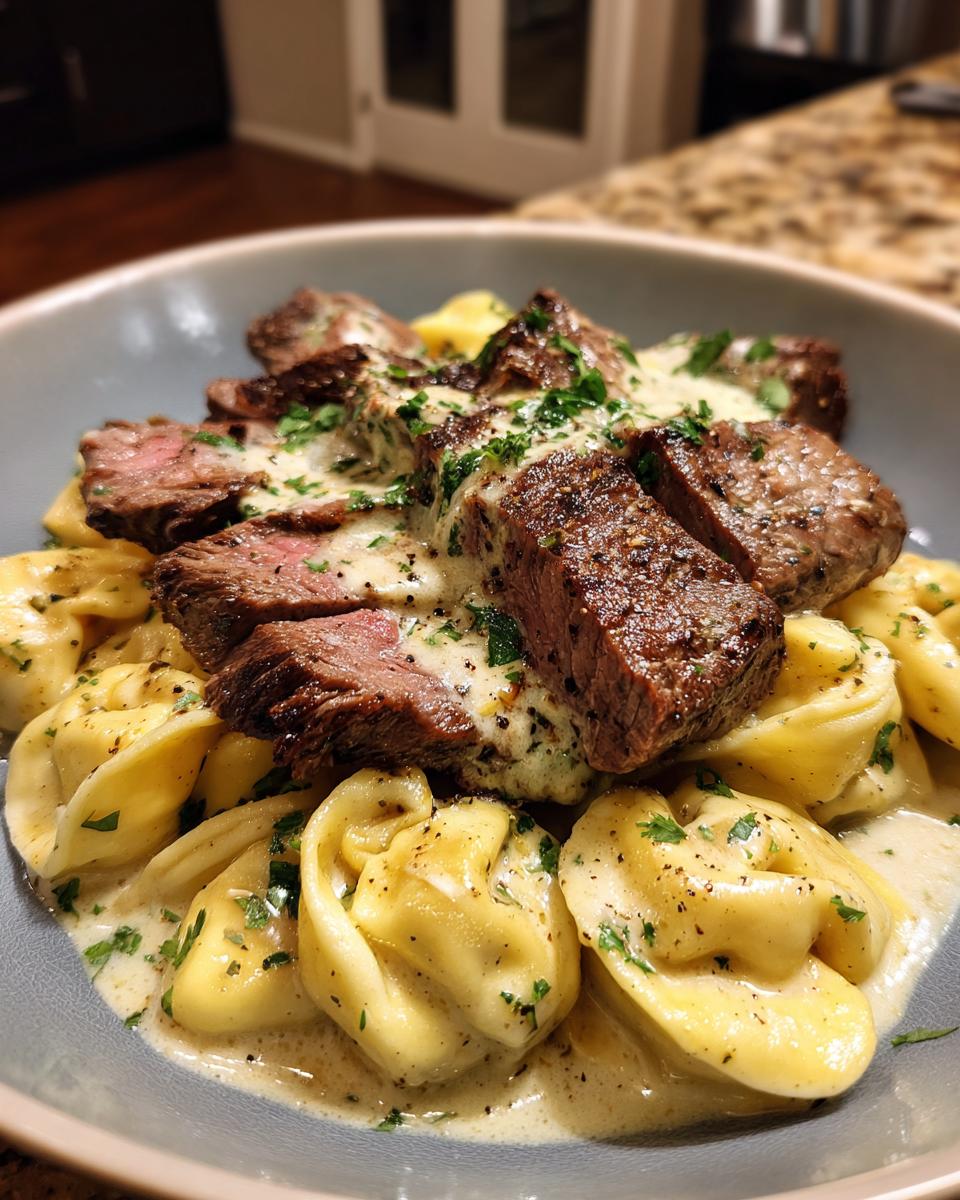 A close-up of Garlic Steak Tortellini served in a bowl with a creamy sauce and fresh parsley.