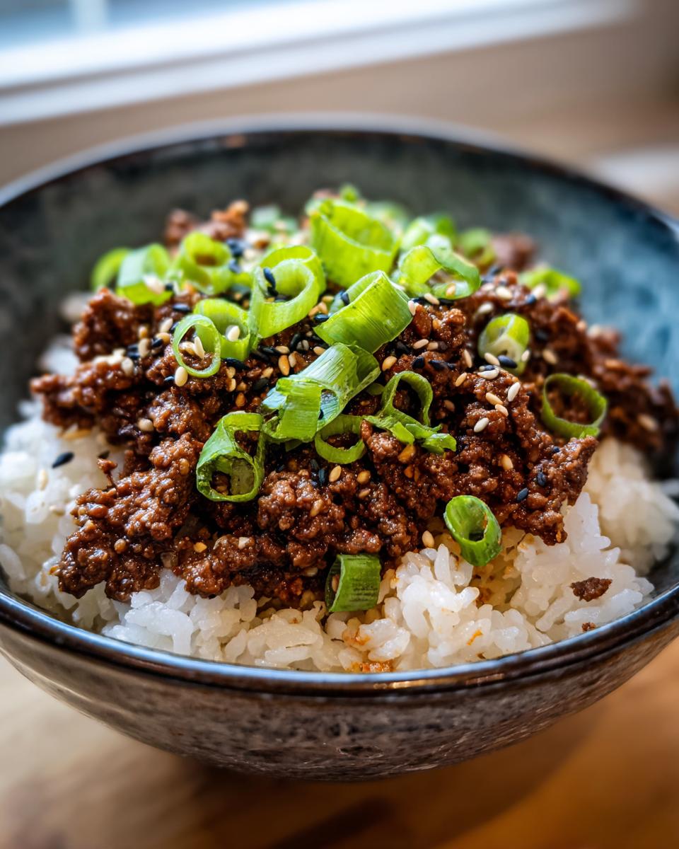 A close-up of a Korean Beef Rice Bowl featuring seasoned ground beef over white rice, topped with green onions and sesame seeds.