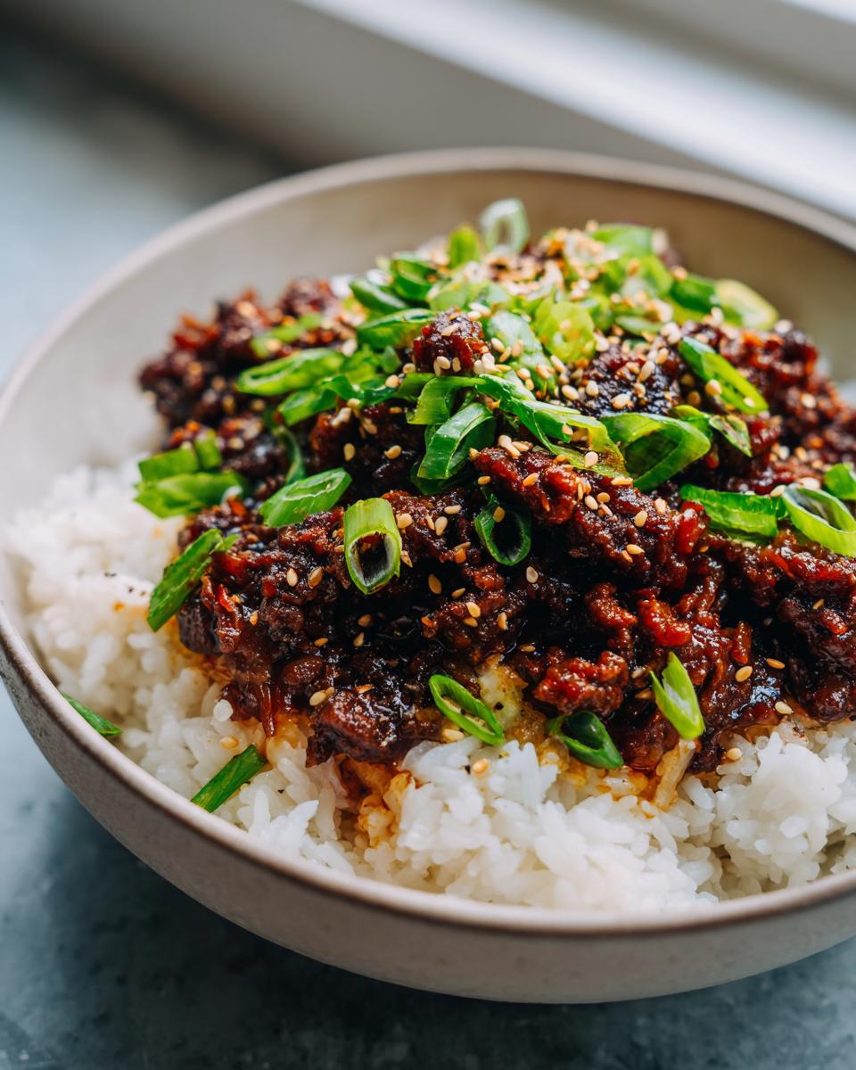 A close-up of a Korean Ground Beef Bowl, featuring savory ground beef over fluffy white rice, garnished with green onions and sesame seeds.