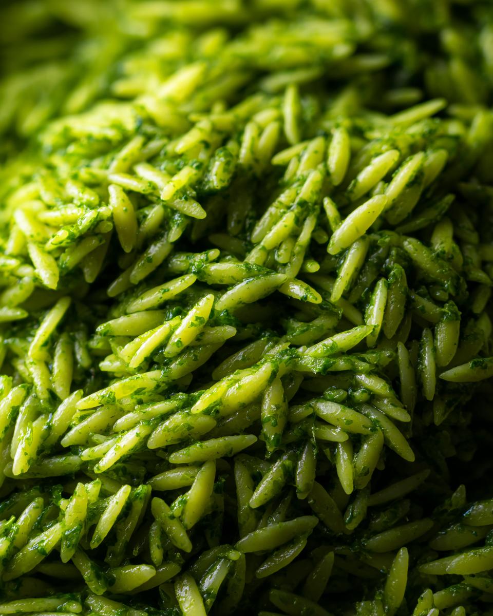 Close-up of bright green pesto orzo pasta, showcasing the vibrant color and texture.