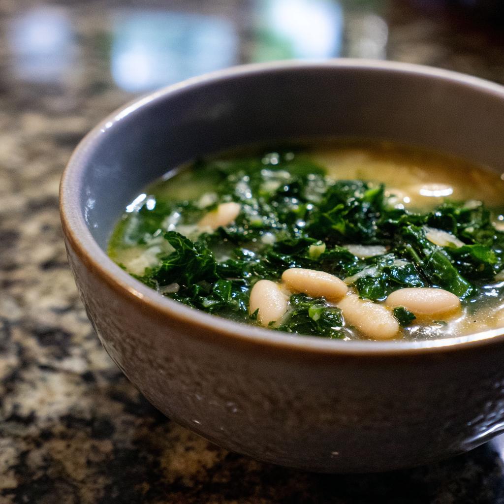 A close-up of a bowl of white bean kale soup, showcasing tender white beans and vibrant green kale in a savory broth.